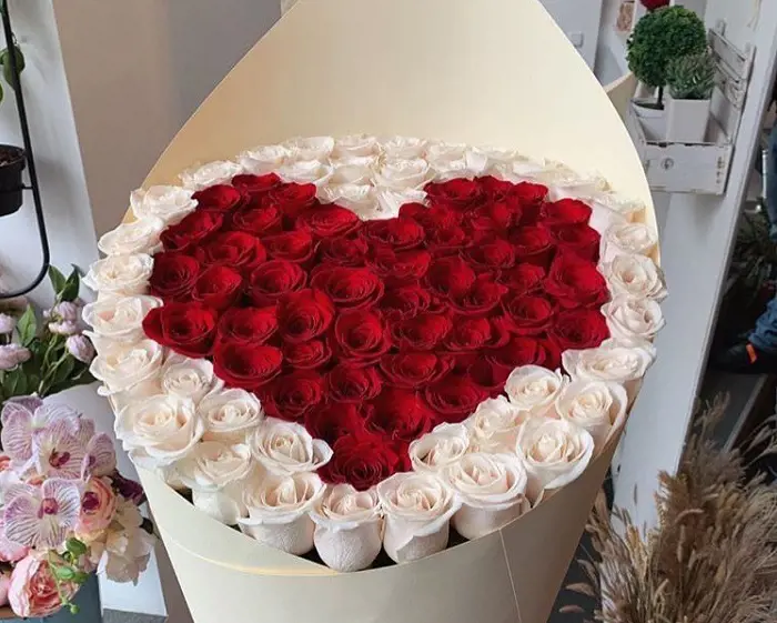 A beautiful white and red rose bouquet in a heart shaped arrangement. 