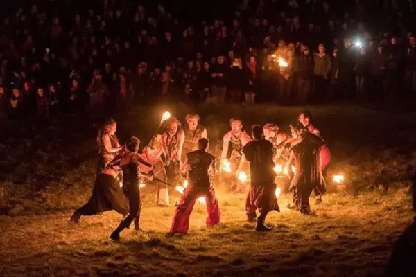 People forming a circle around bonfire as part of traditional Beltane celebration.