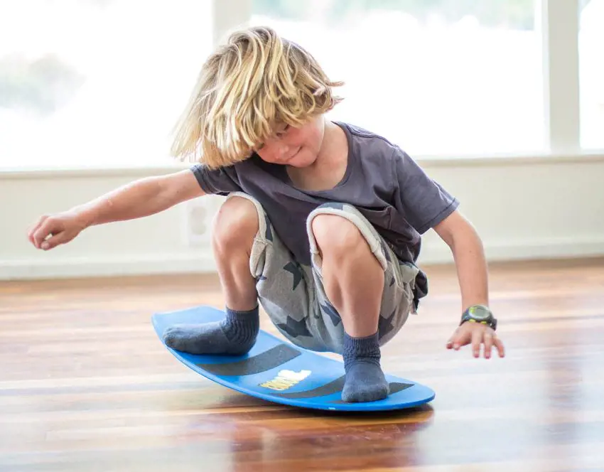 Kid practices balancing on a spooner board