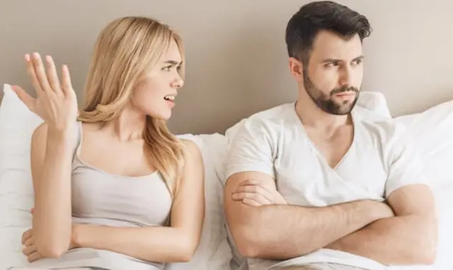 A woman tries to have a conversation with her partner who is lost in his own thoughts during bedtime