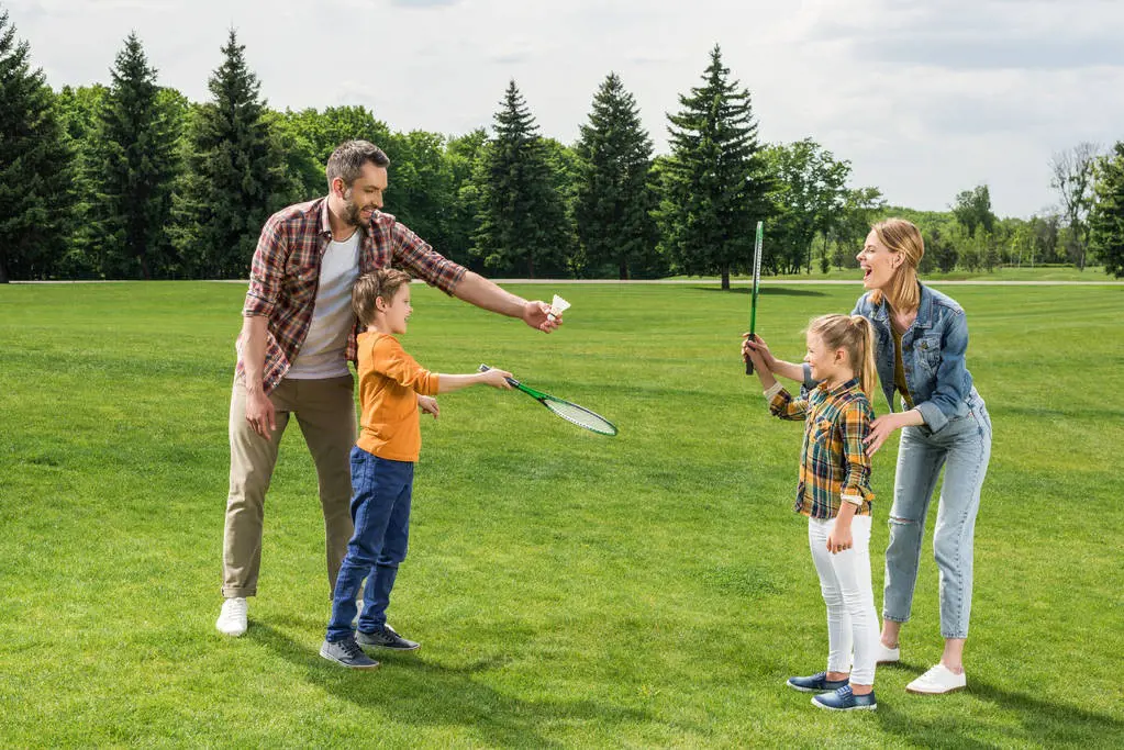Father teaching his children to play badminton