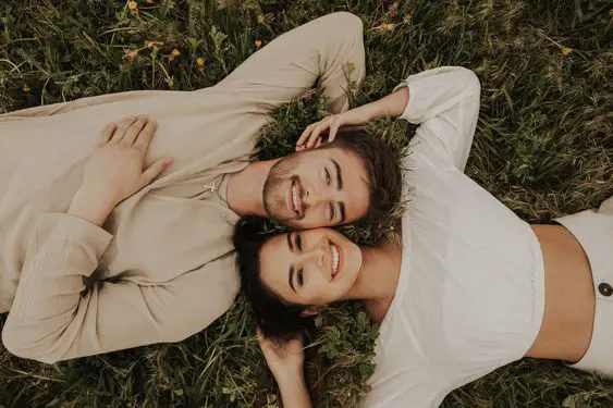 Lovers lay on the grass field as they look toward photographer Amanda Wood while the adorable moment is captured