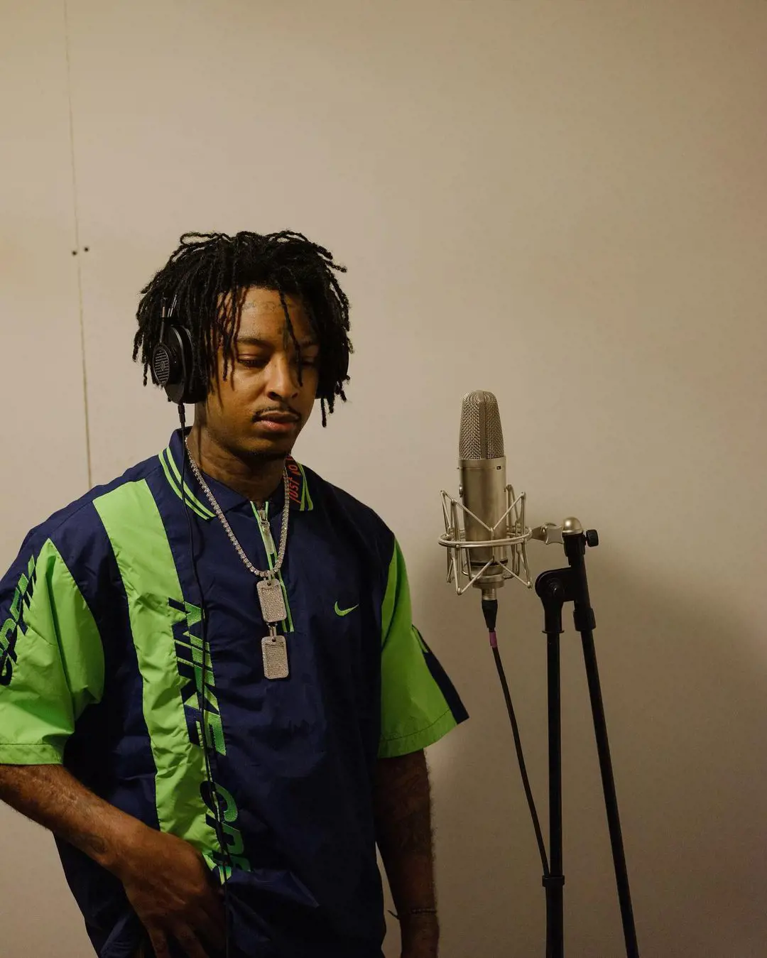 Rapper 21 Savage recording a song in Miami Florida where he is seen wearing a green t-shirt and dreadlocked hair. 