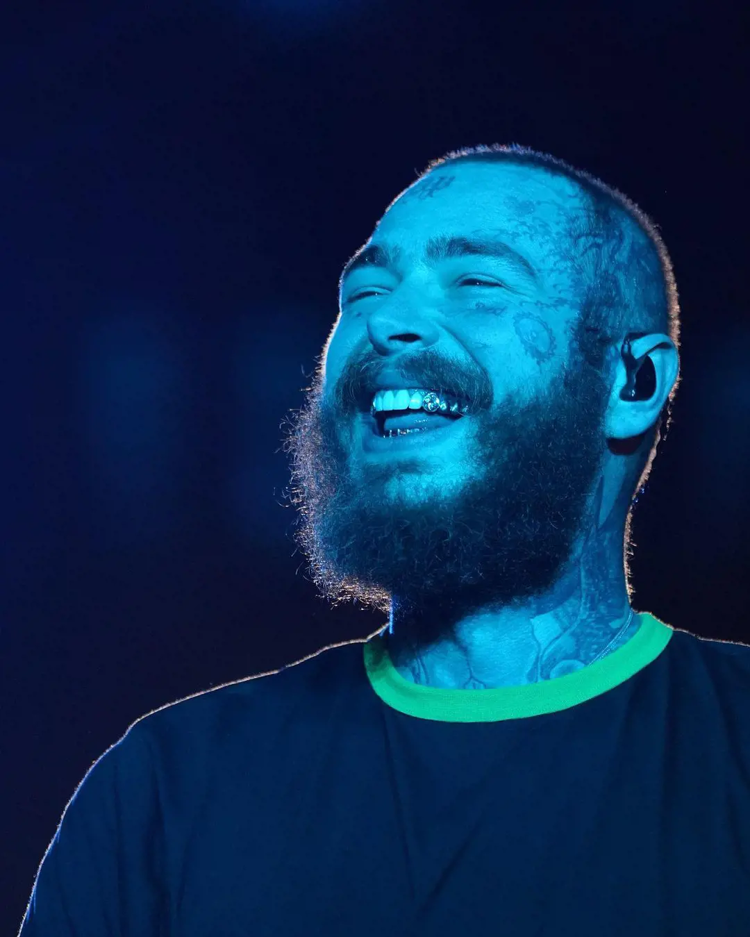 Rapper Post Malone performs onstage with a prominent smile showing his golden tooth pictured by his personal photographer Adam Degross