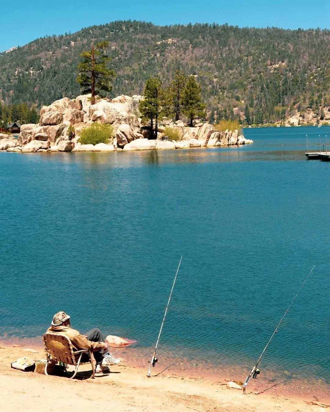 A man relaxes with is fishing rod in Big Bear Lake, California