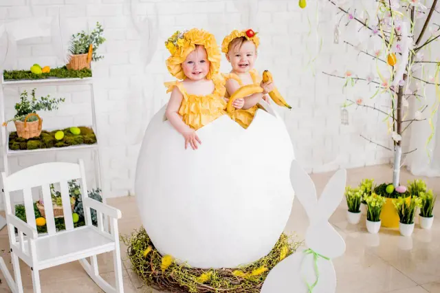 Two beautiful children sit on a steroid egg shaped chair in a well decorated room