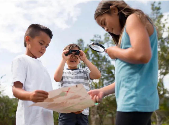 Two kids look at a map with clues about the location of treasure as another looks through binoculars