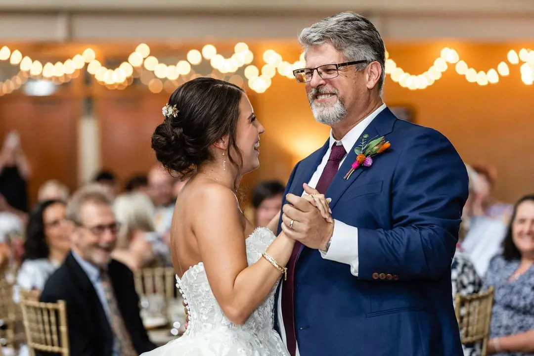 A father and a daughter dances on the wedding day with a joyful expression on their face
