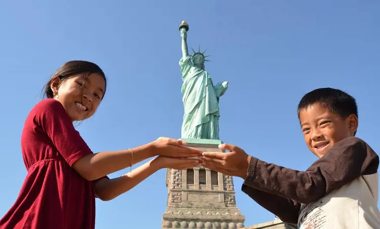 A small boy and a girl pose with the Statue of Liberty in New York City.