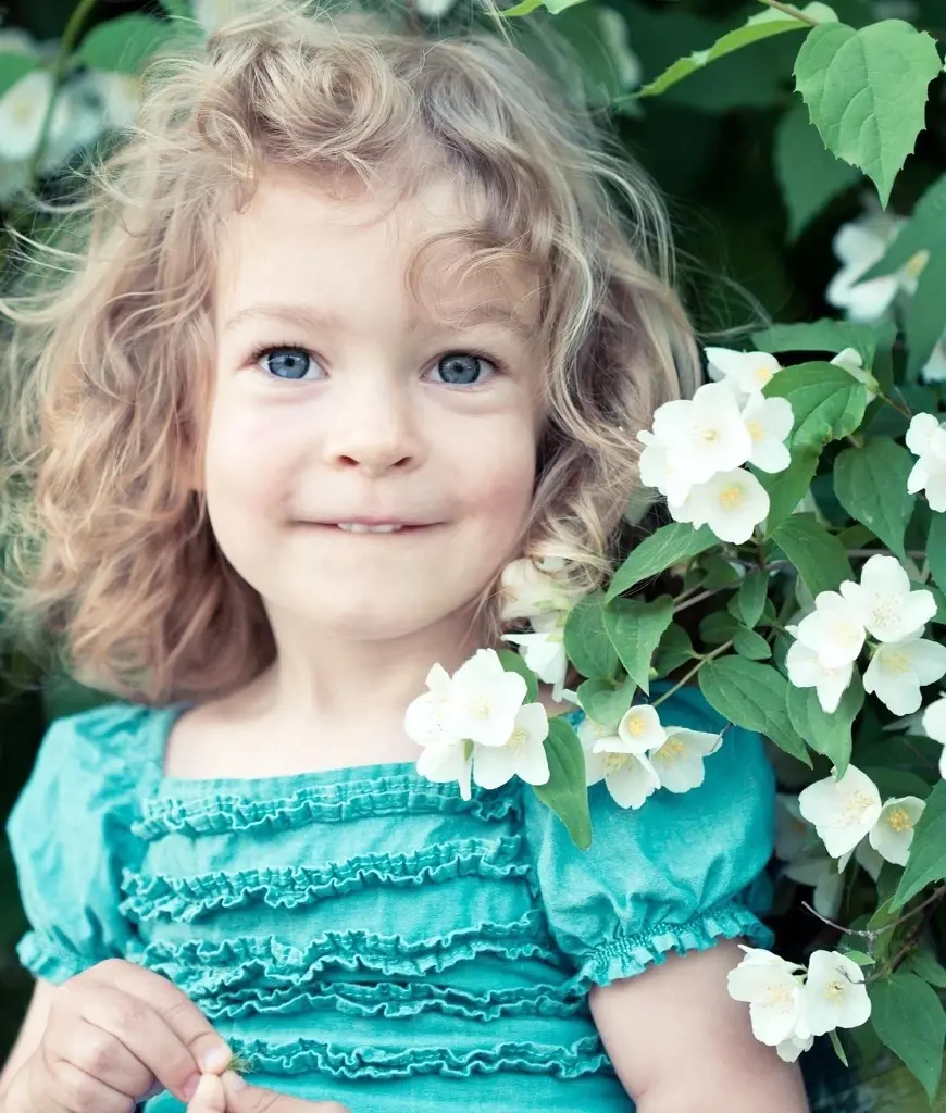 In a spring park a joyful child holds jasmine flowers radiating happiness and embracing nature beauty