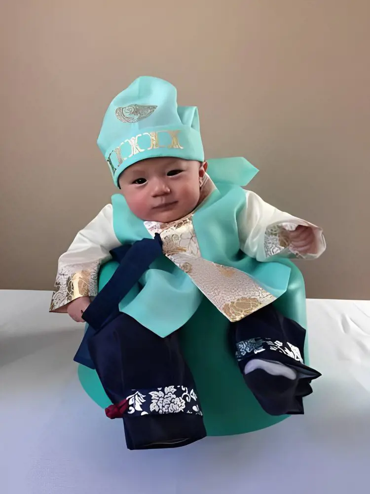 A young one attired in a hanbok for his 100 days birthday