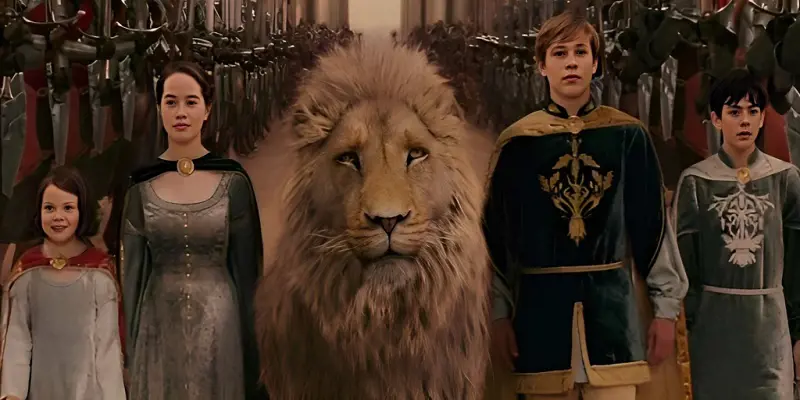 The Chronicles of Narnia characters (L-R) Lucy, Susan, Aslan, Peter, and Edmund stand side by side. 