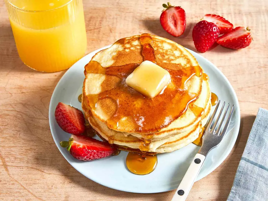 Hot and delicious pancakes with a slice of butter, honey and some strawberries 