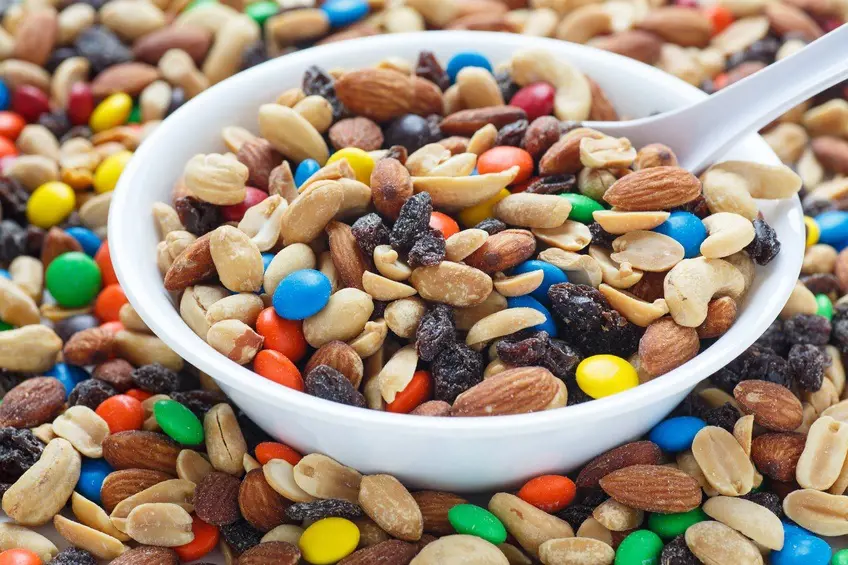 A bowl full of mixed nuts and chocolates  looks colorful and tasty