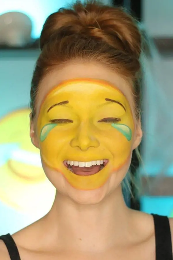 Woman face paints laughing with tears emoji