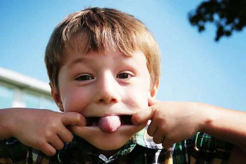 Young kid makes a funny face as he sticks out his tongue 
